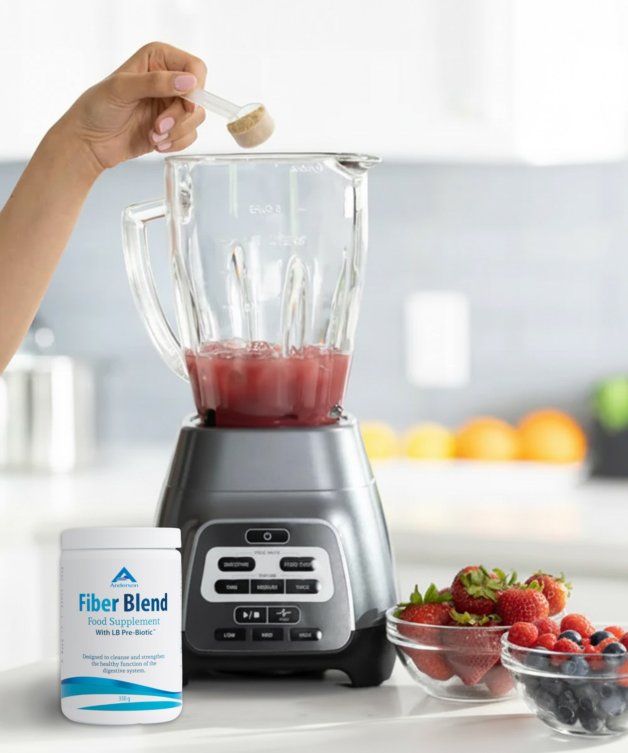 Hand adding fiber blend supplement powder to blender with berries on kitchen counter