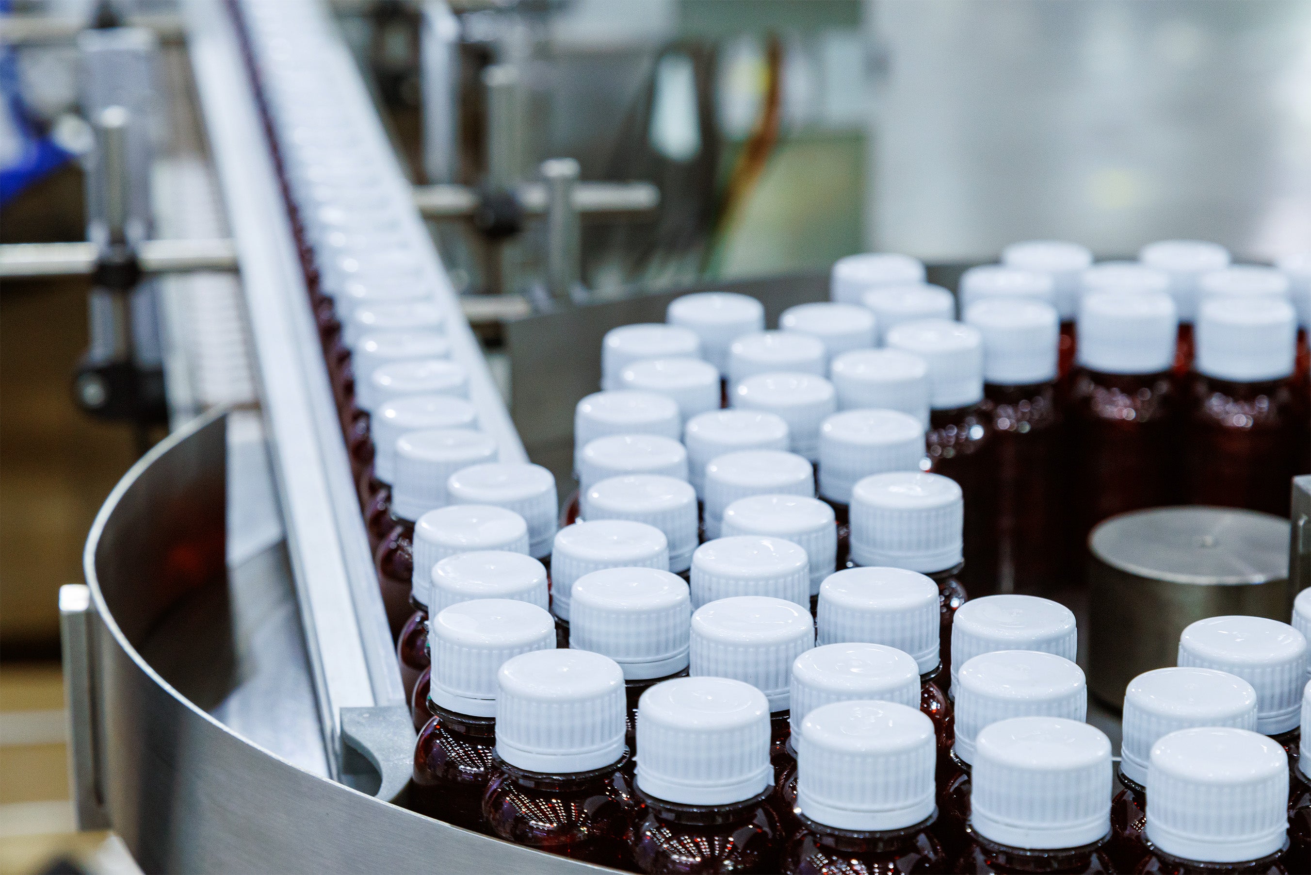 Supplement bottles with white caps on production line in a manufacturing facility