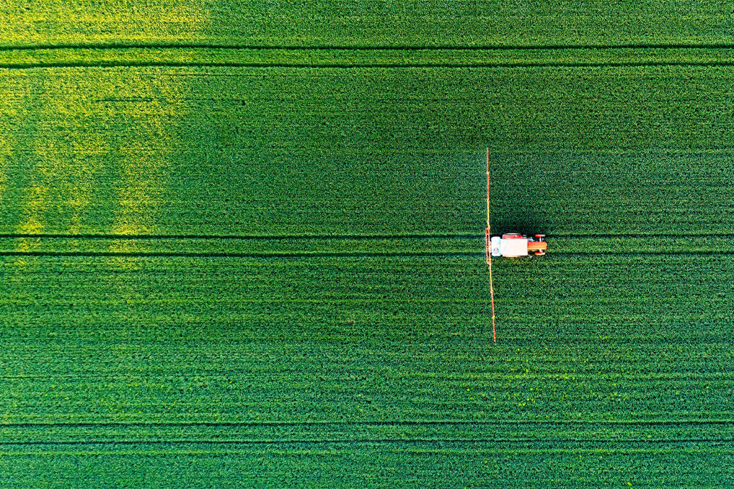 Aerial view of a tractor in a green field