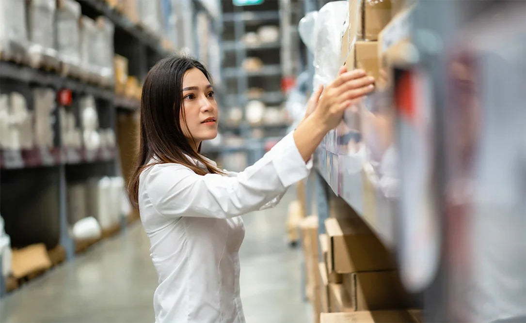 Woman in a warehouse setting, interacting with shelves.