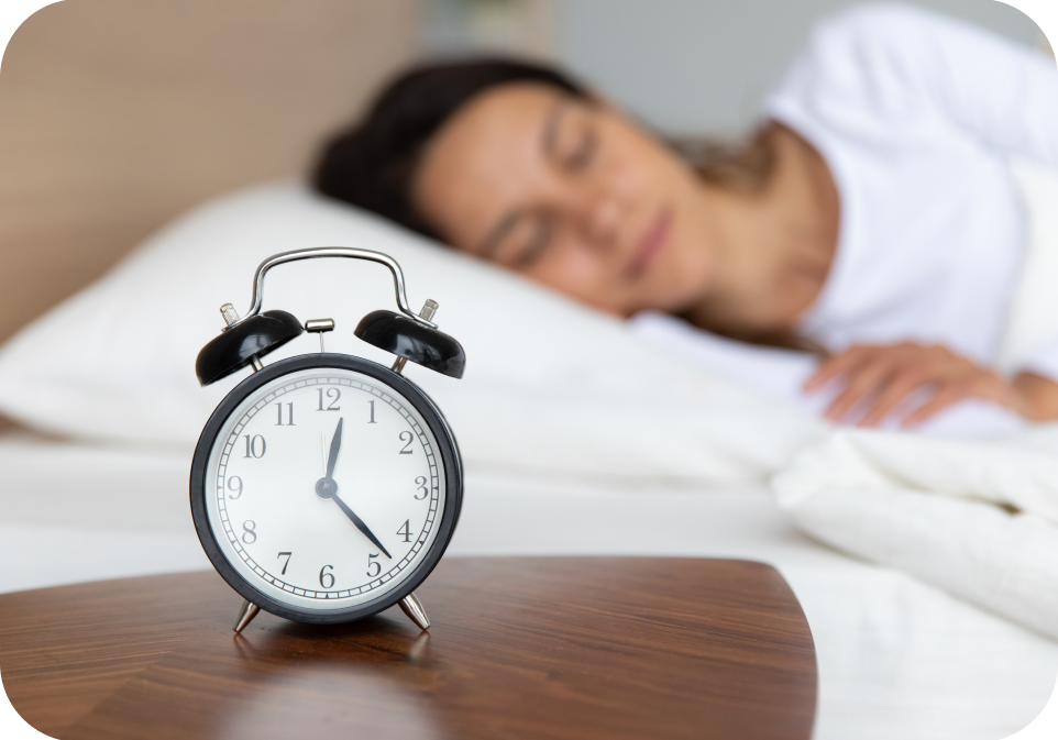 Woman lying in bed with an alarm clock on a nightstand